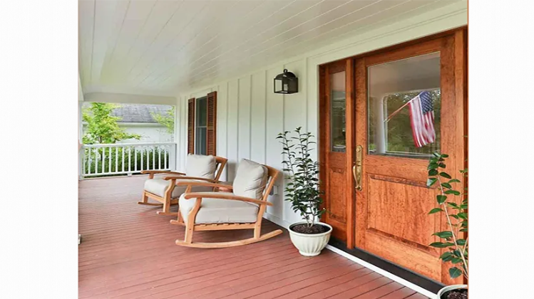 There are two rocking chairs on the porch of a house.