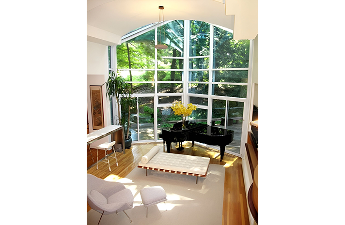 A living room with a piano and lots of windows