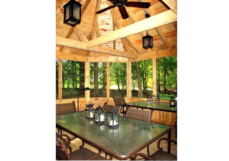 A screened in porch with a table and chairs and a ceiling fan