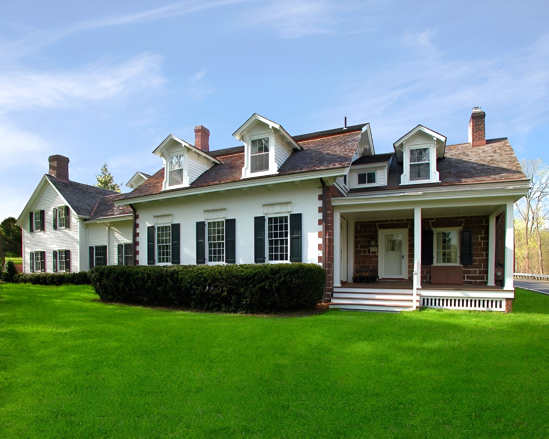 A large white house with black shutters and a porch