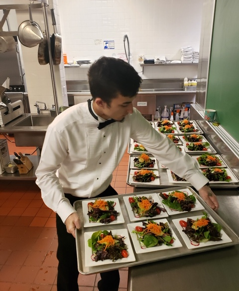 A man in a tuxedo is holding a tray of food