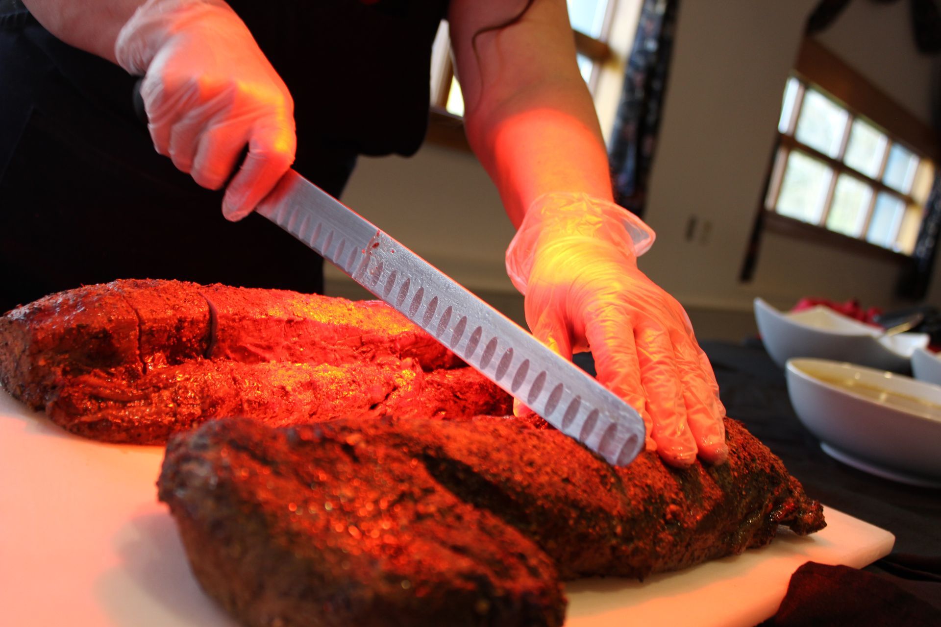 A chef is cutting a large piece of delicious meat on a cutting board.