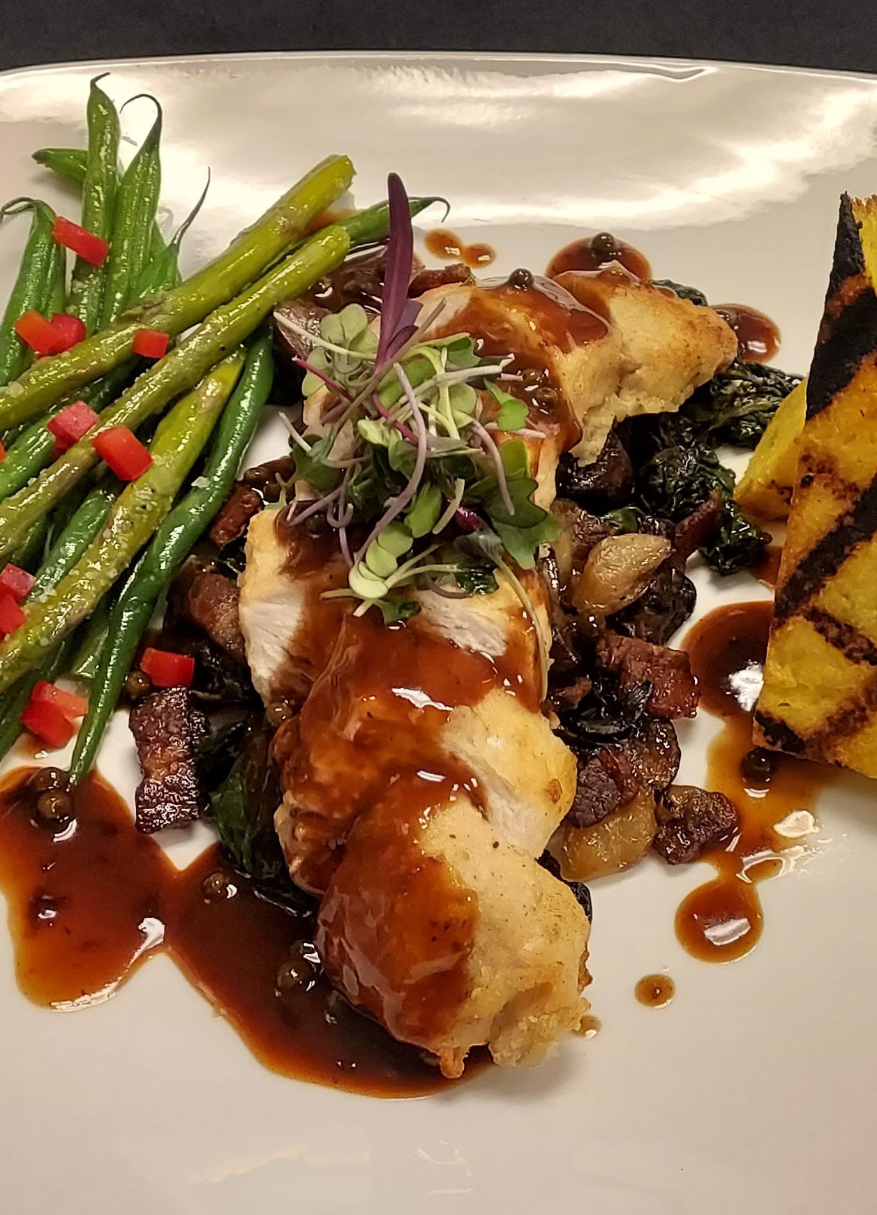 A white plate topped with chicken, green beans and polenta.