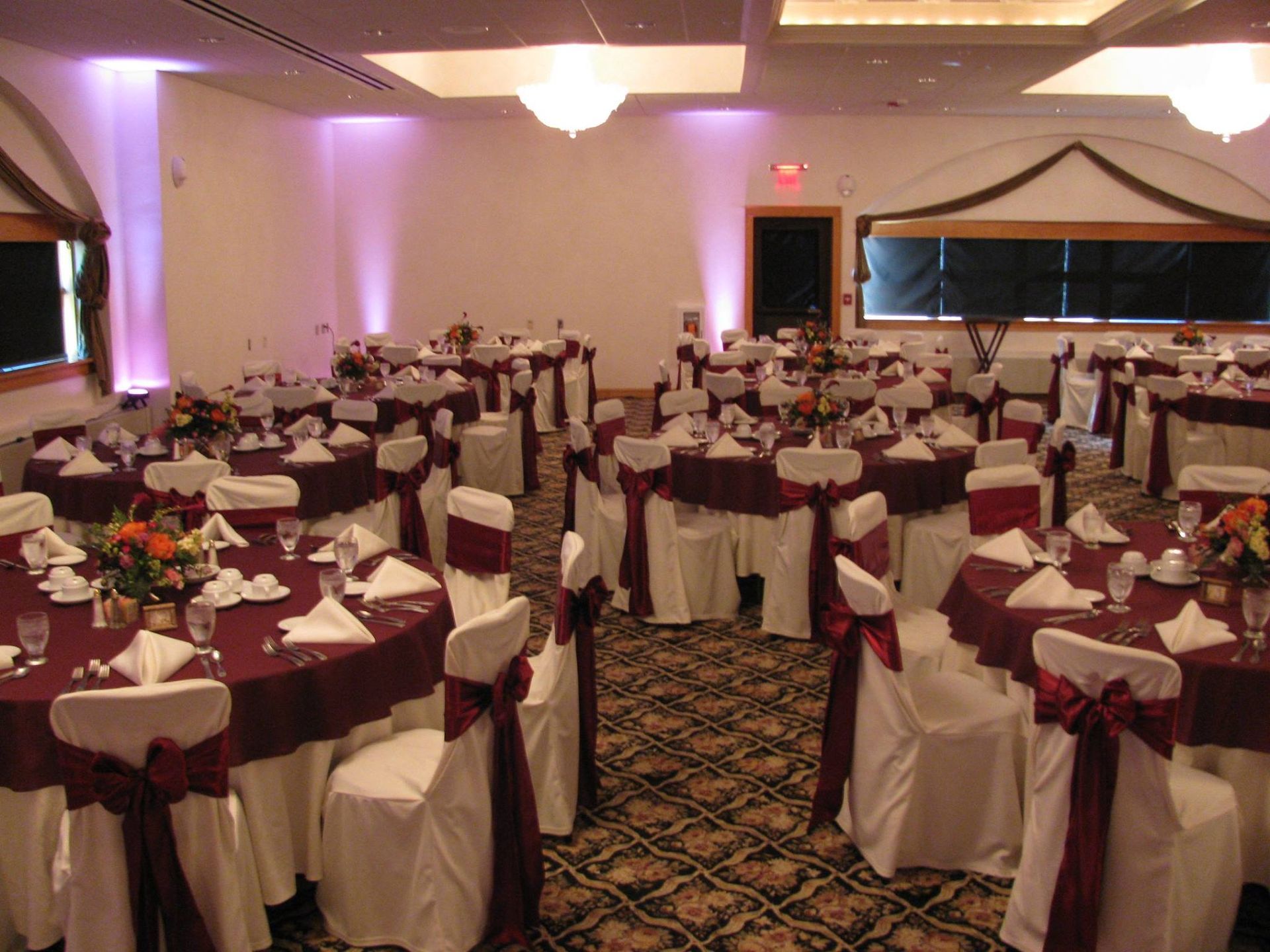 A large room with tables and chairs set up for a wedding reception.