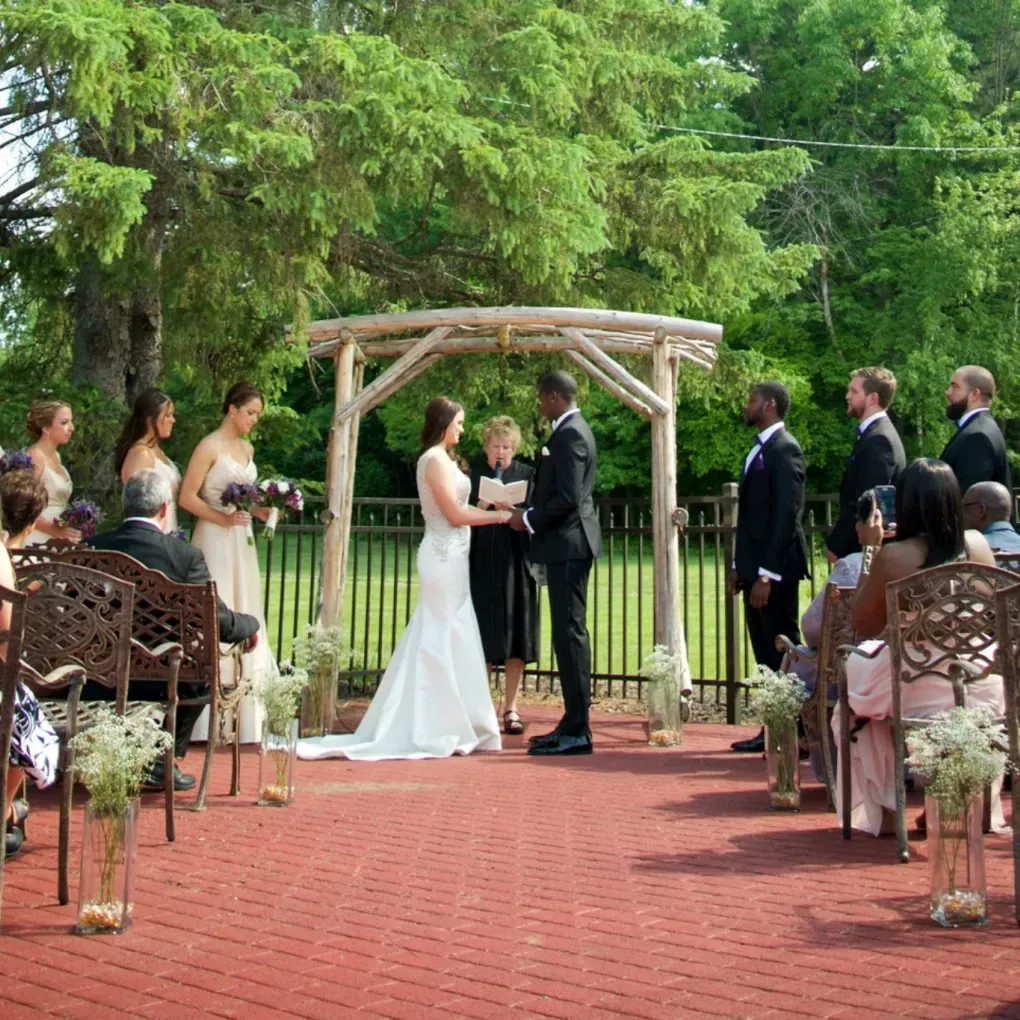 A bride and groom are holding hands during their outdoor wedding ceremony on the West Side Patio.