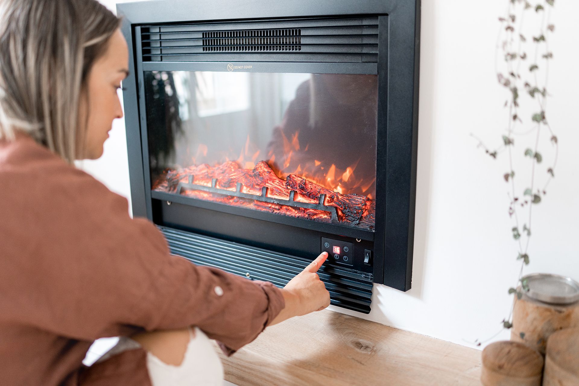Una donna è seduta davanti a un camino elettrico.