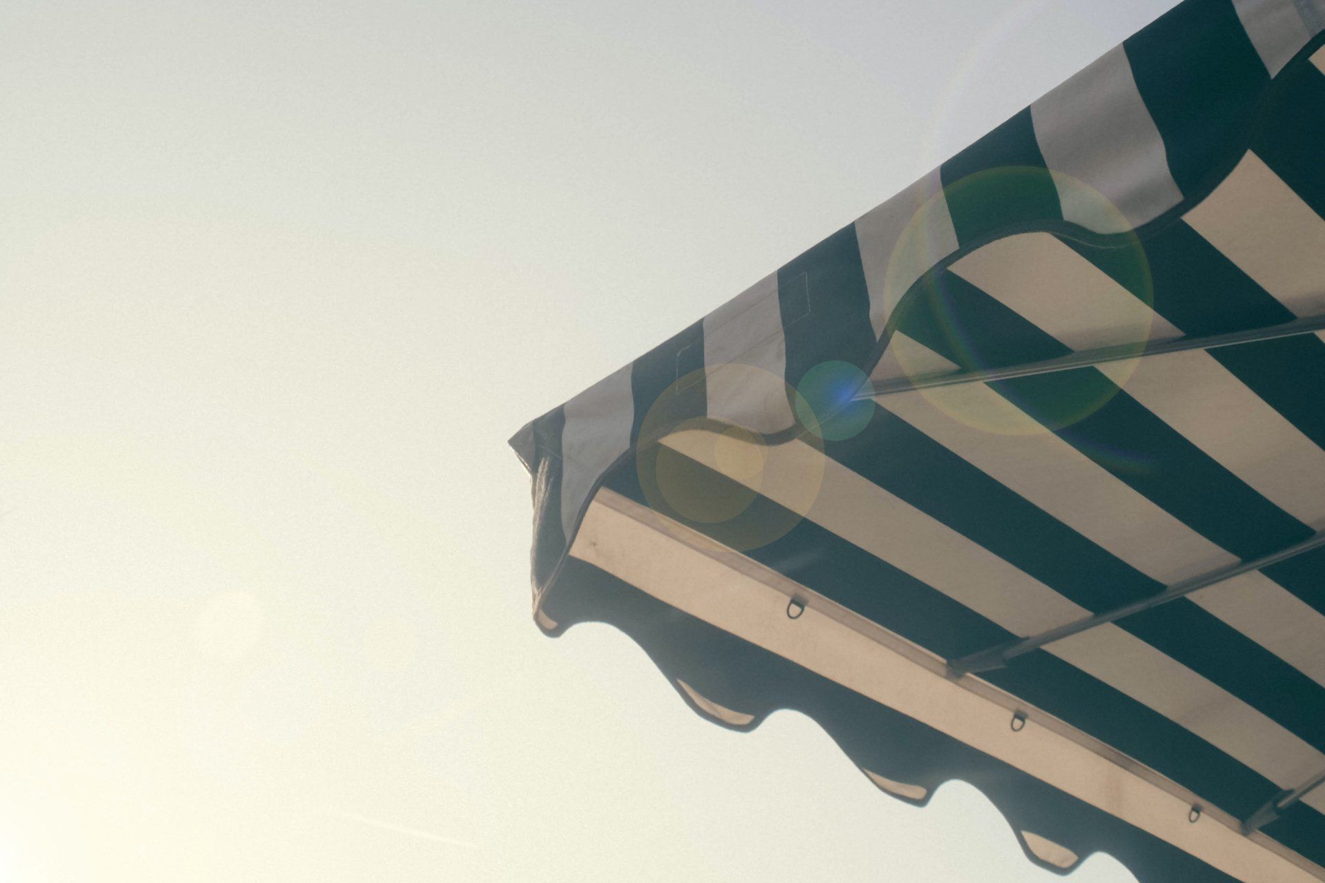 Una tenda da sole a strisce bianche e nere si staglia contro un cielo blu.