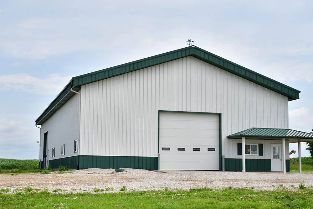 A white building with a green roof and a white garage door