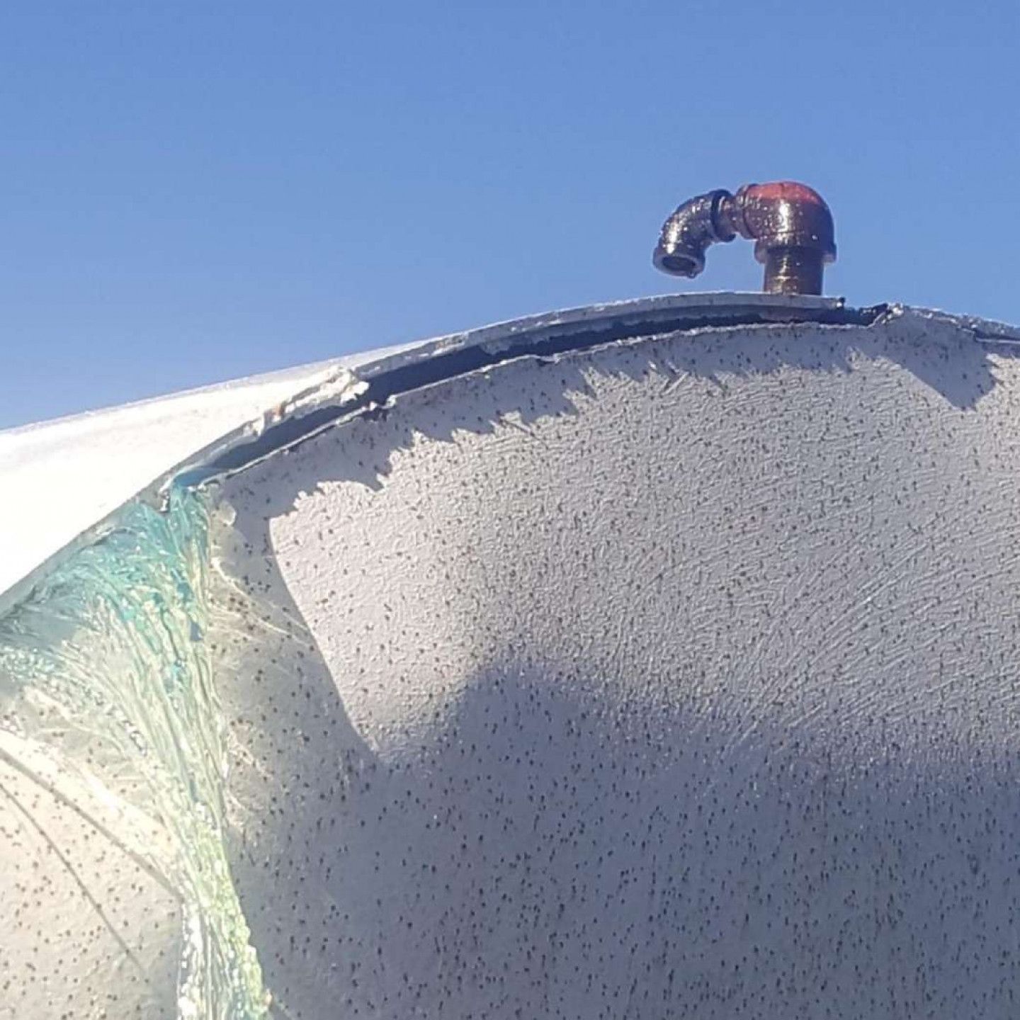 A pipe on top of a white object with a blue sky in the background