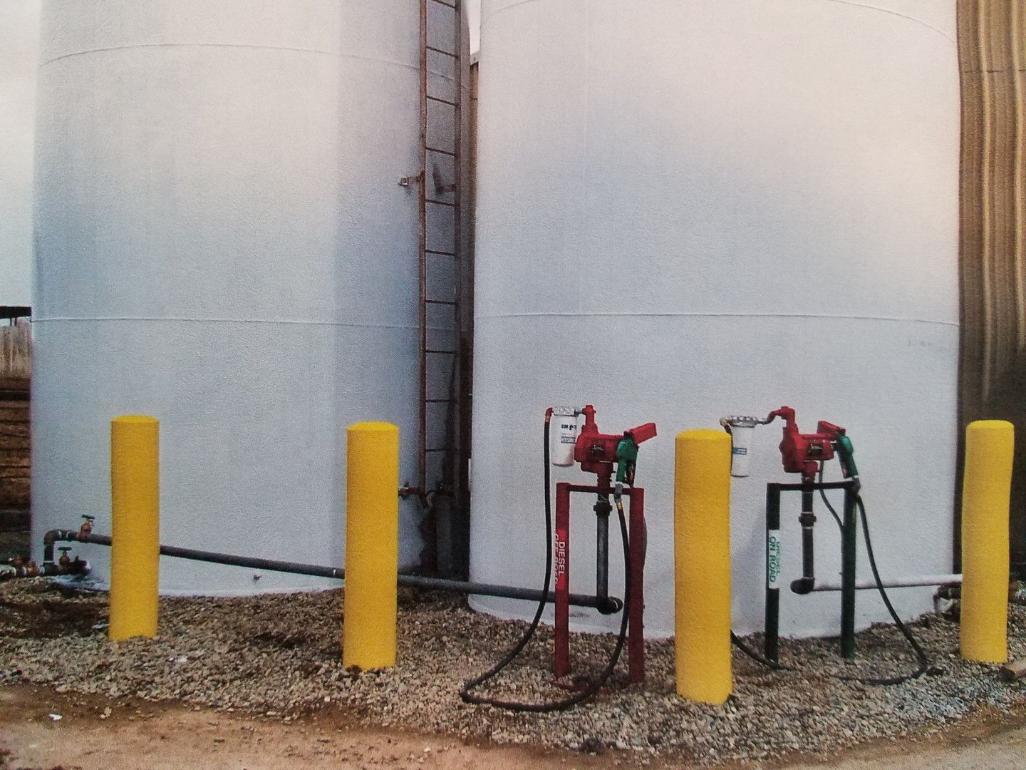 A row of yellow poles in front of a white tank