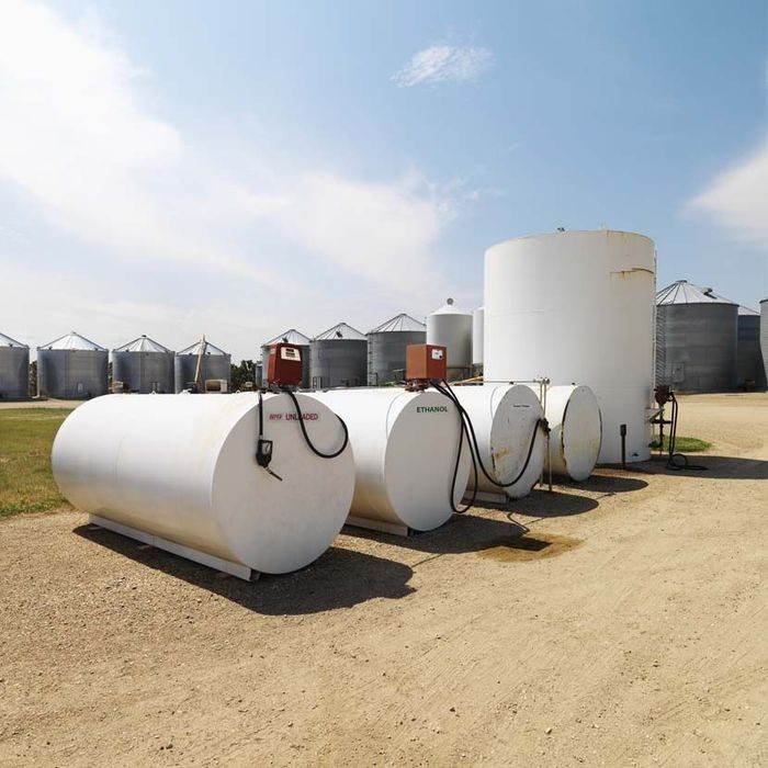 A row of white tanks are lined up in a dirt field