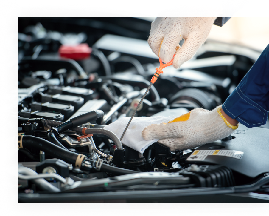 Gloved hands checking a car engine with a dipstick in a garage