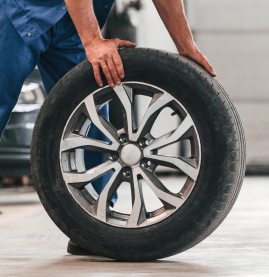 Person rolling a car tire with alloy wheel in a garage