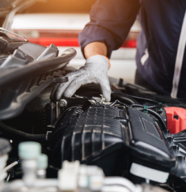 Mechanic wearing gloves inspecting a car engine under the hood