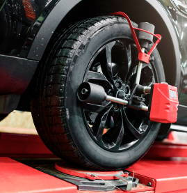 Car wheel on a red alignment rack with a wheel clamp attached
