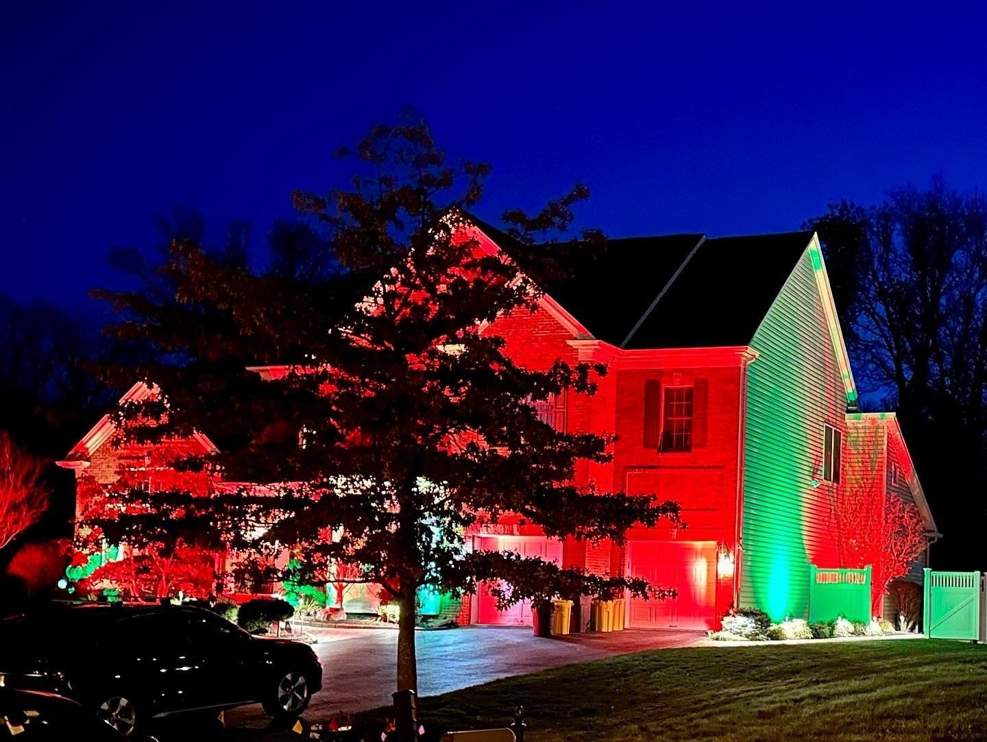 House lit with red and green lights for Christmas at night.