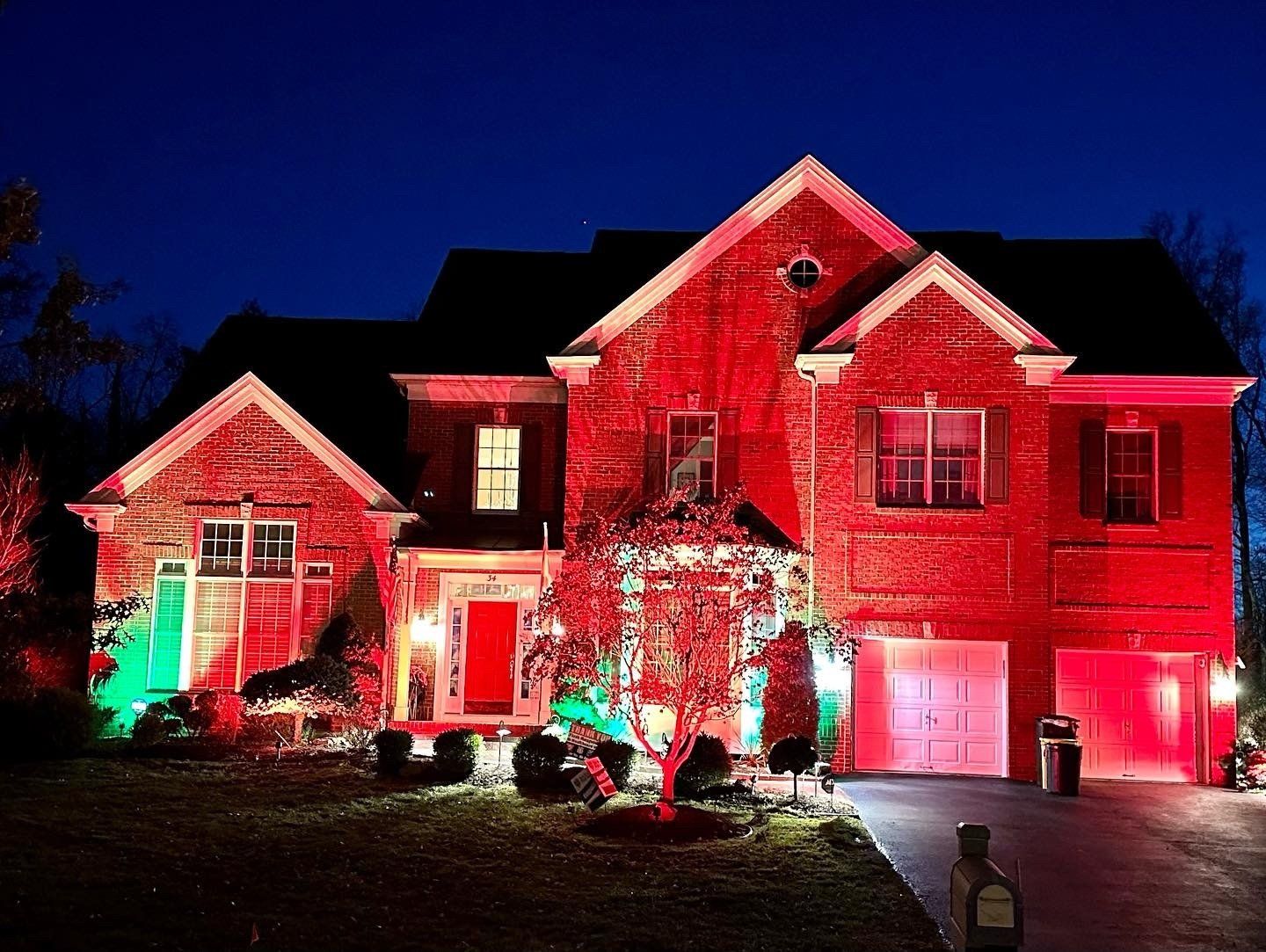 House exterior illuminated with red and green lights for the holidays.