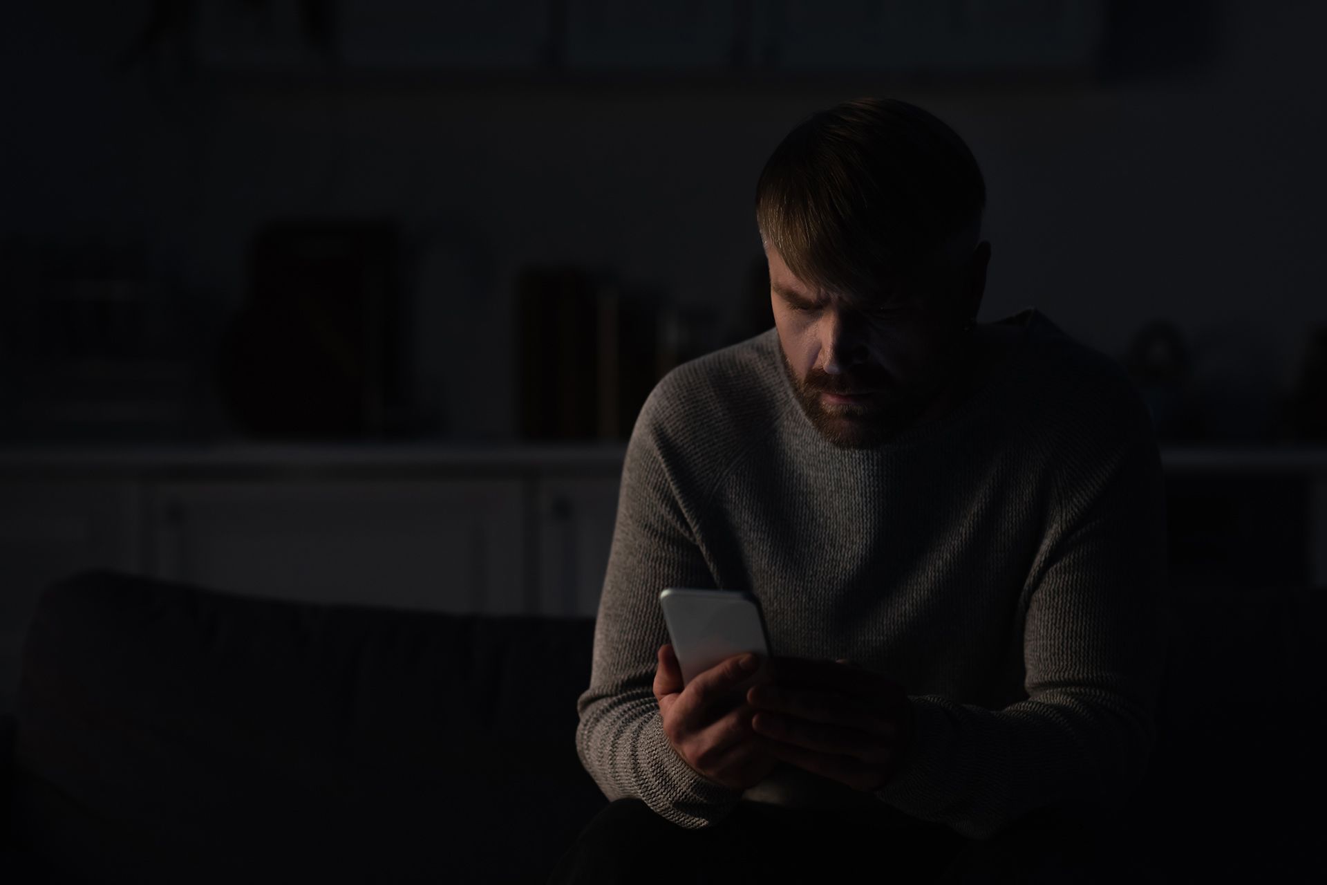 Person using a phone in a dark room during a power outage after an electrical failure.