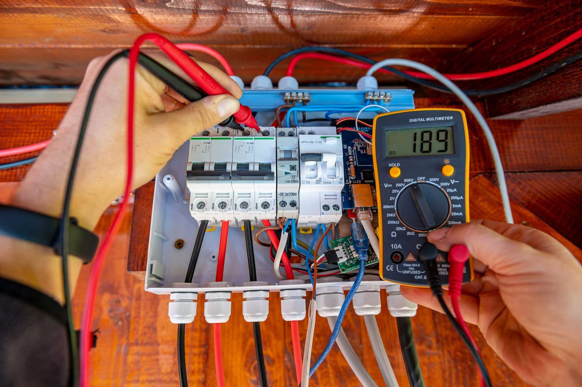Hand of an electrician, performing emergency electrical repair, with a multimeter probe.