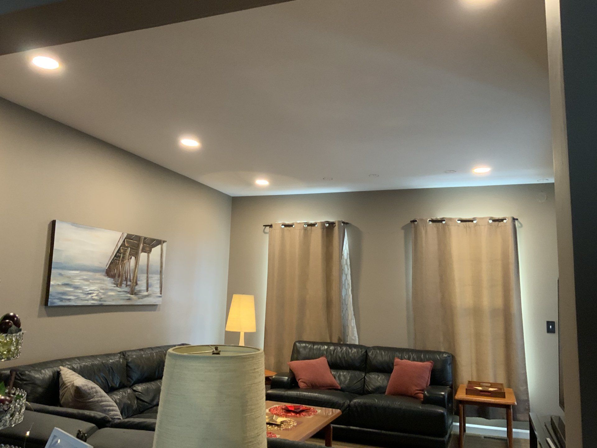 Living room with sectional sofa, recessed lighting, and curtains.