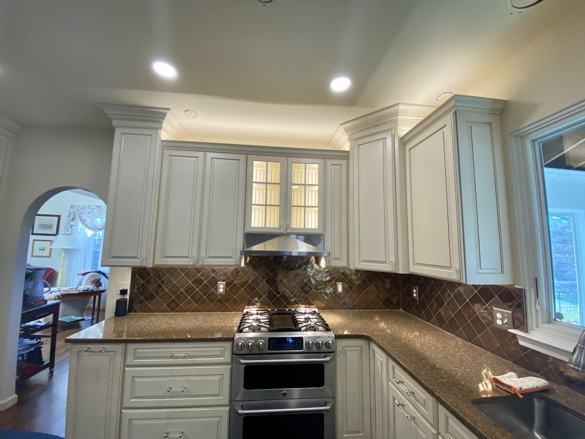 Kitchen with white cabinets, brown backsplash, and stainless steel oven.