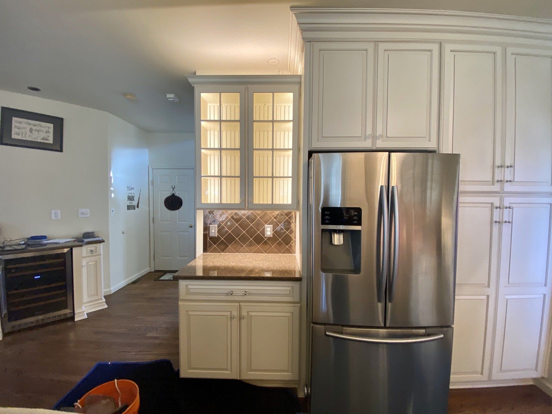 Kitchen with stainless steel refrigerator, white cabinets, and a counter with tile backsplash.