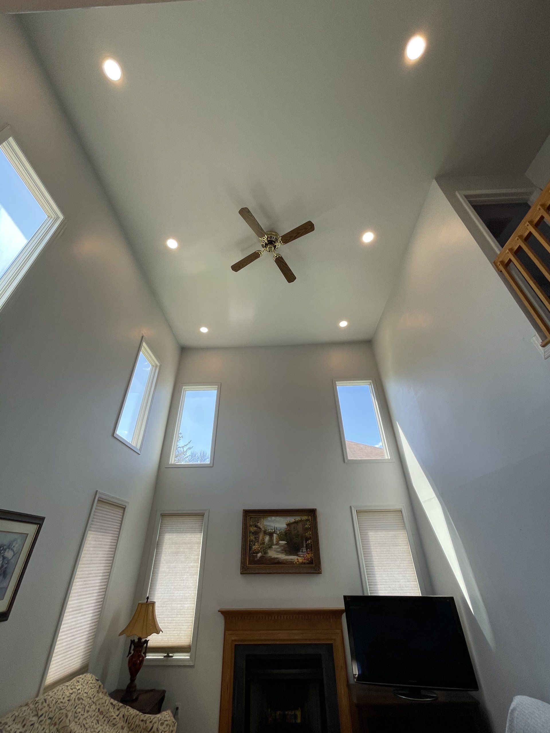 High-ceilinged living room with a fireplace, windows, recessed lights, and a ceiling fan.