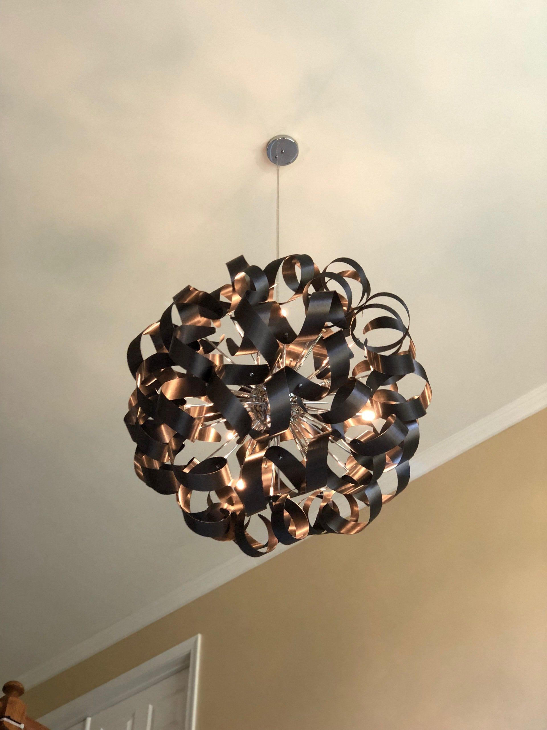 Black and copper orb-shaped pendant light hanging from a white ceiling.