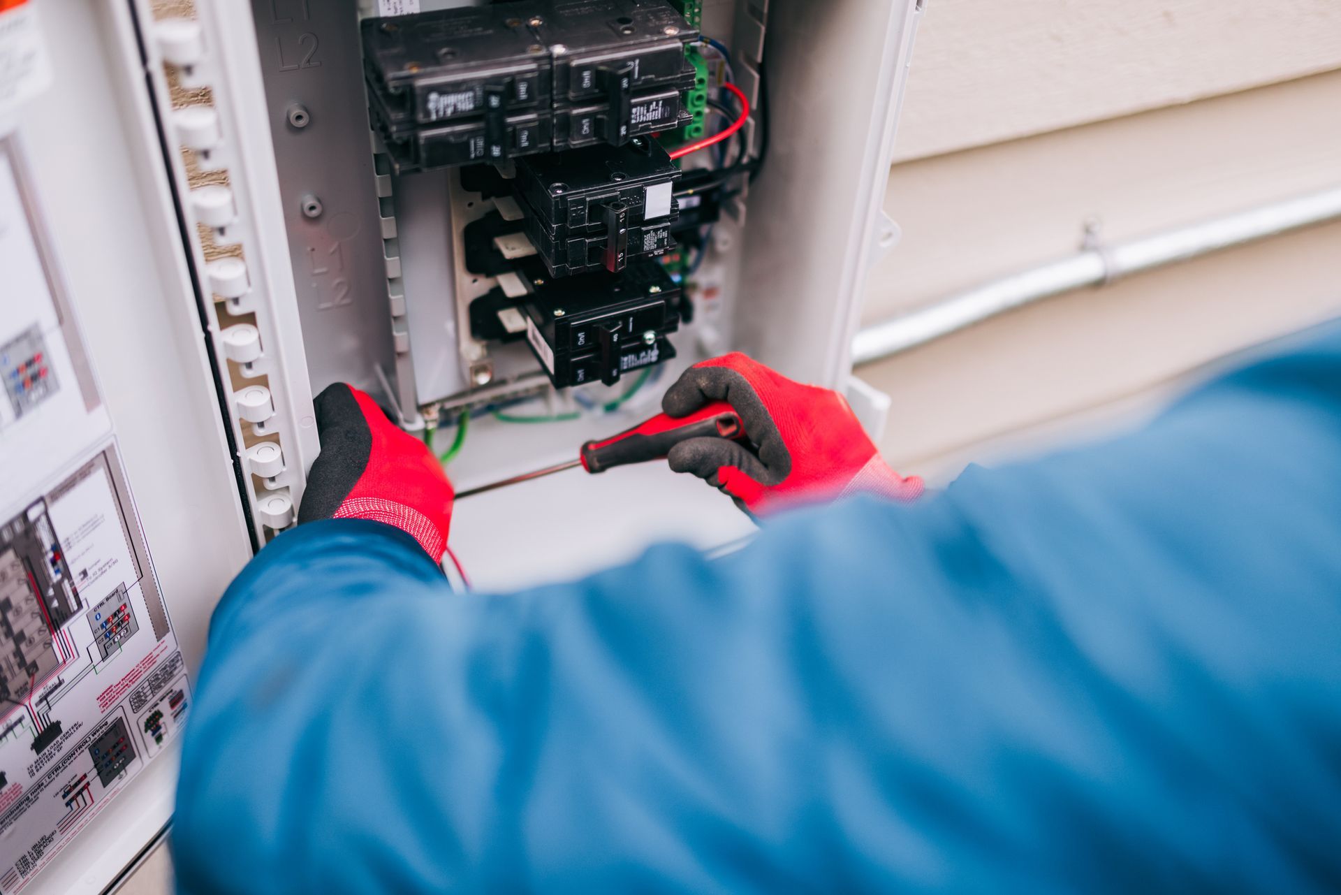 A male electrical contractor working on a breaker box, as parts of electrical services.