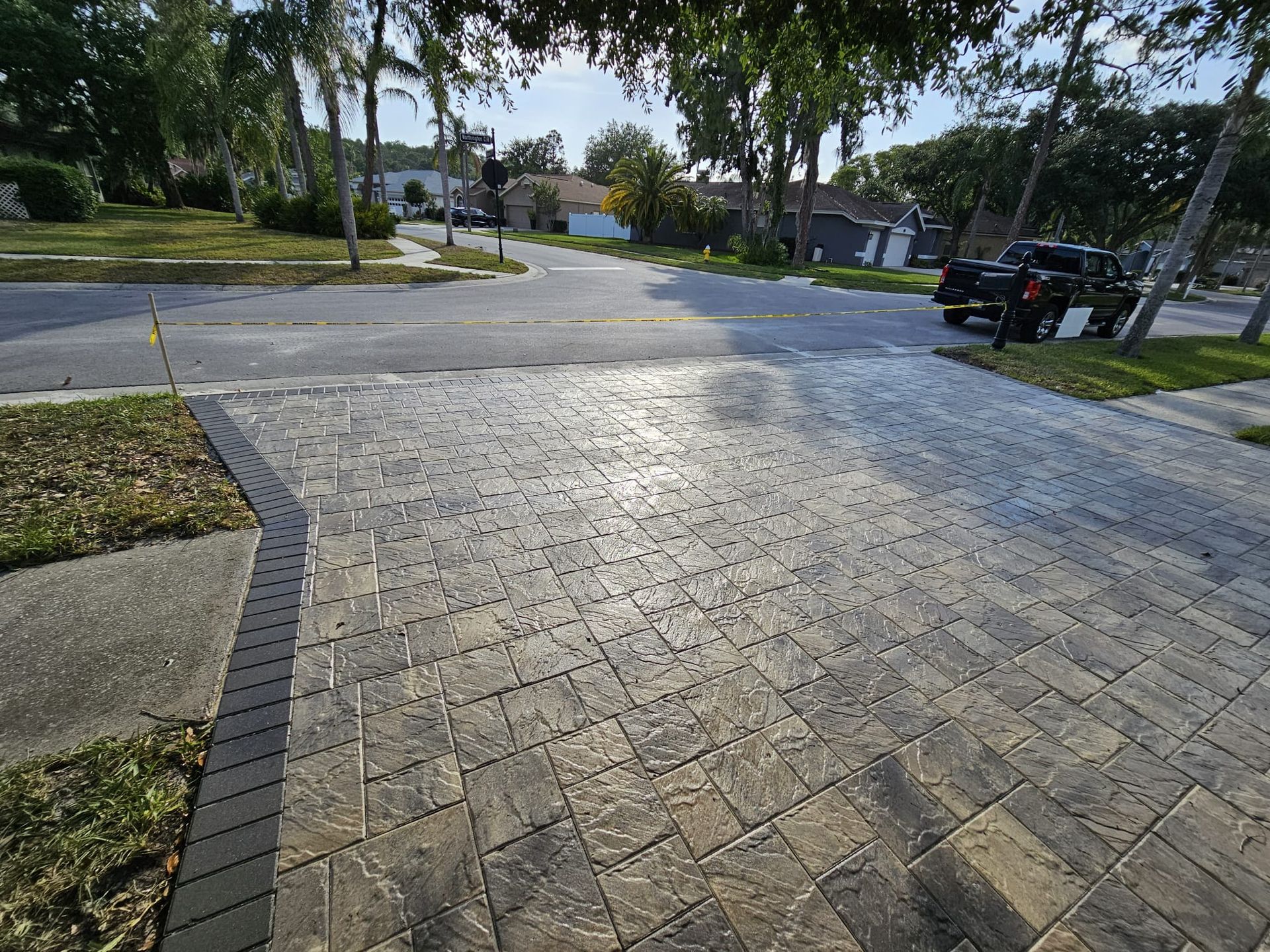 Driveway paved with textured blocks; street and houses in the background.