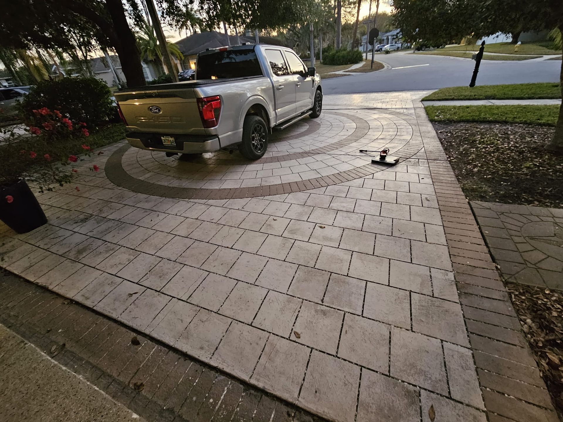 A light-colored pickup truck parked on a brick driveway in front of a house.