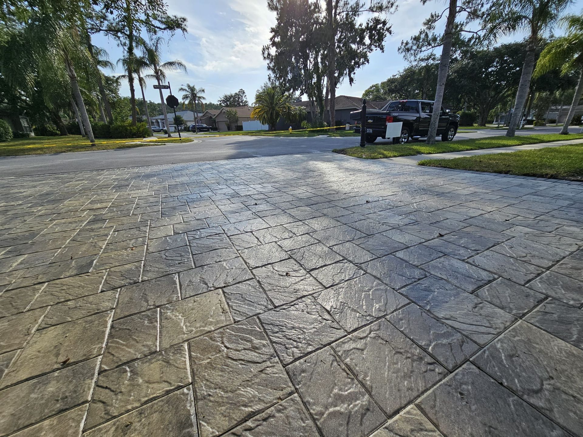 Stamped concrete driveway with a textured pattern and sunlight.