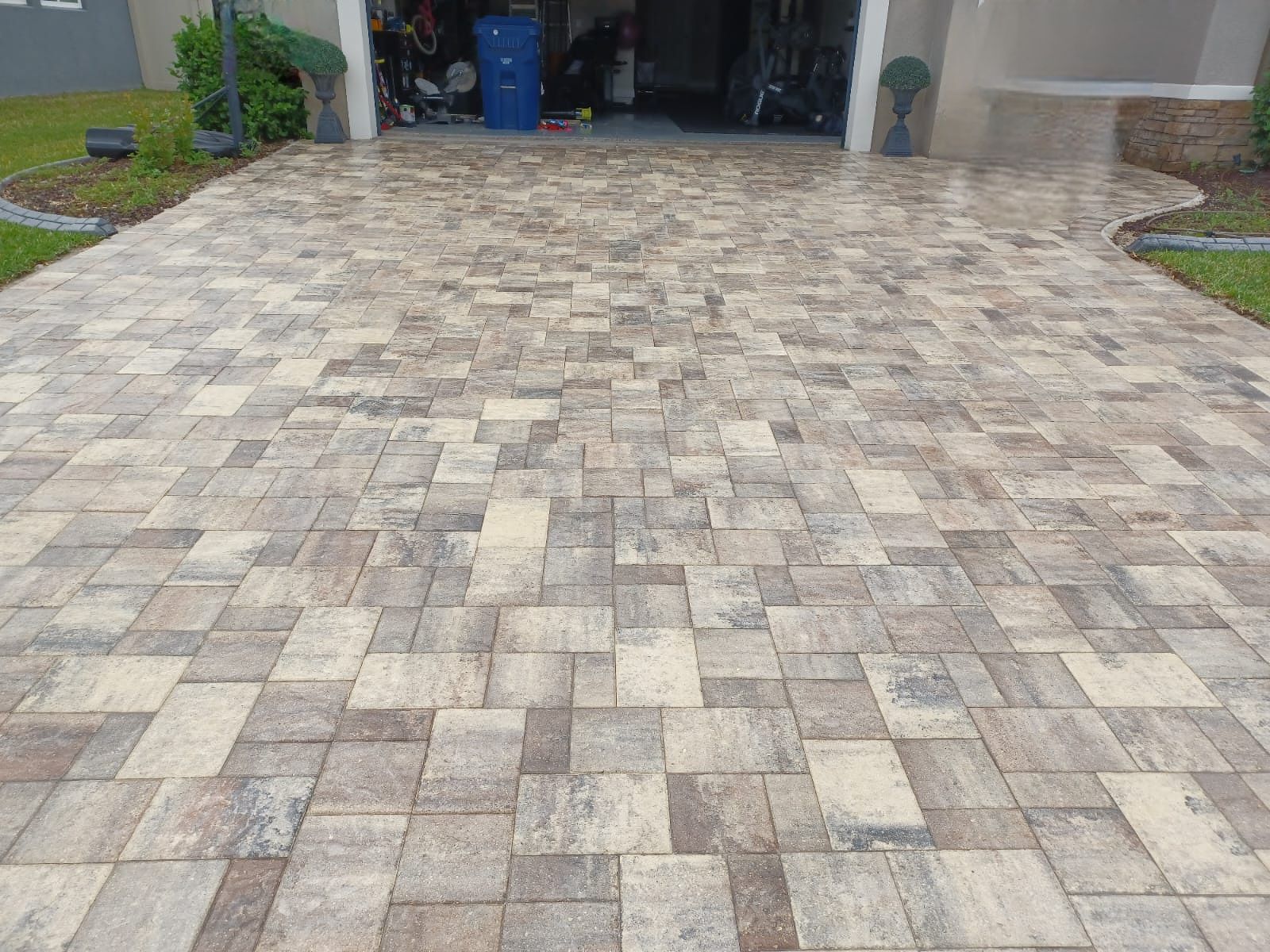 Brick paved driveway leading to a garage. The bricks are varying shades of brown and gray.