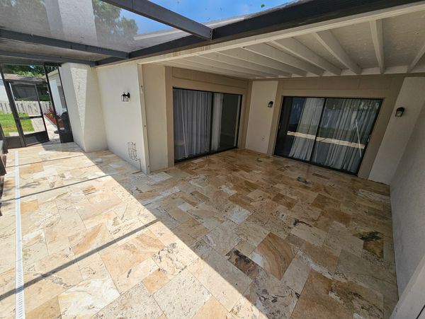 Covered patio with tiled floor, sliding glass doors, and white walls.