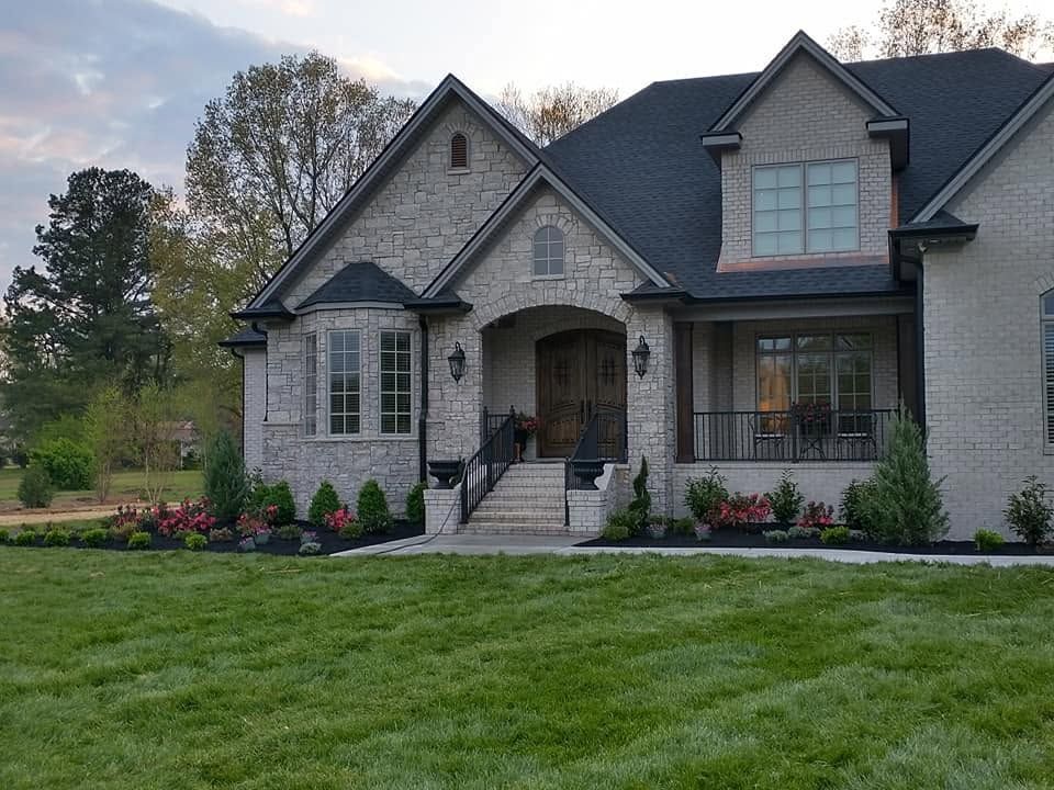 large home with freshly laid sod and flower beds