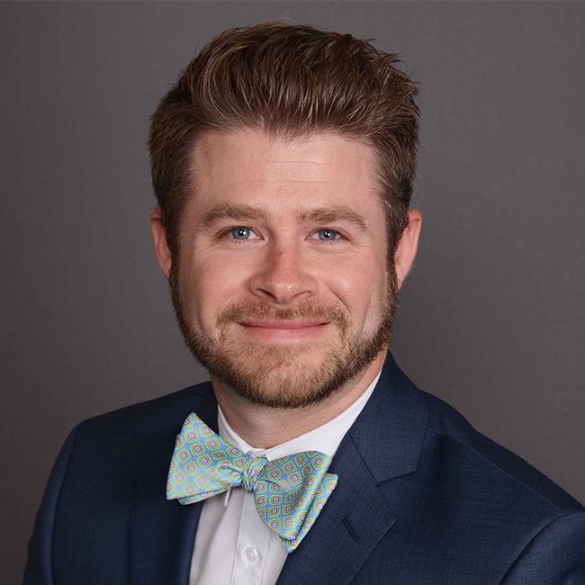 A man with a beard is wearing a suit and bow tie.