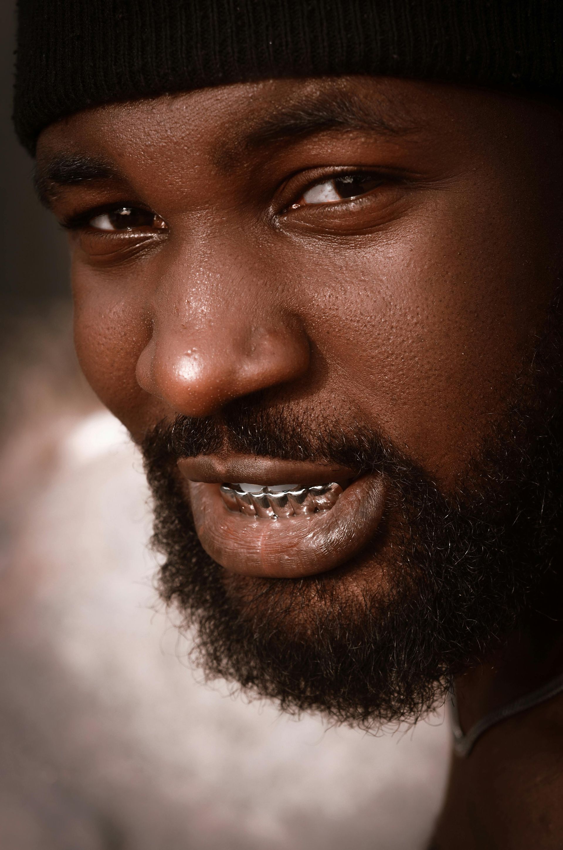 Sparkling grin of a confident Black man porting custom grillz.