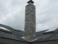 a stone chimney on top of a roof with skylights
