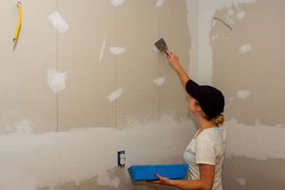 a woman is plastering a wall with a spatula .