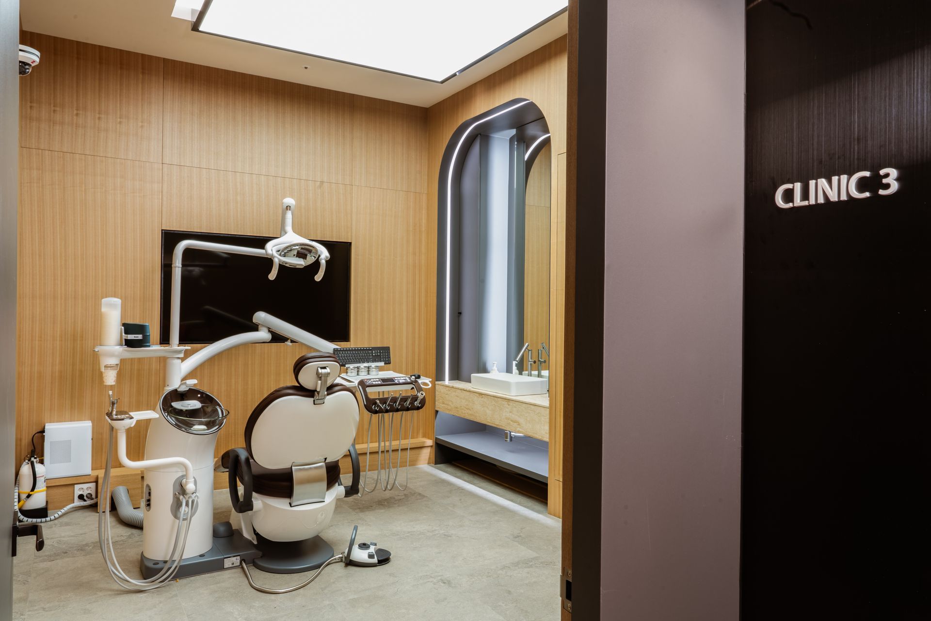 Dental clinic room with chair, equipment, and a sink area. 