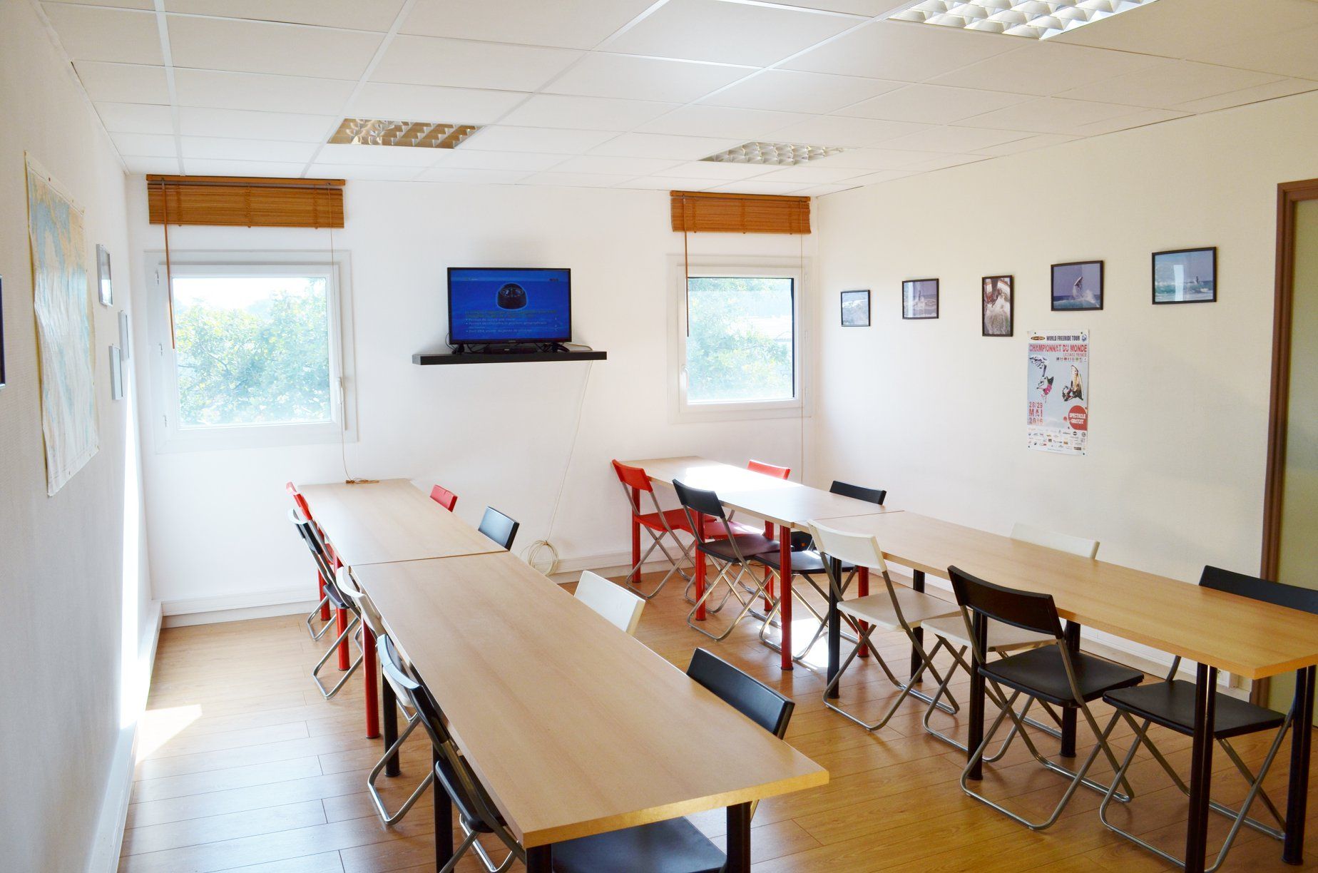 Une pièce avec des tables et des chaises et une télévision au mur.