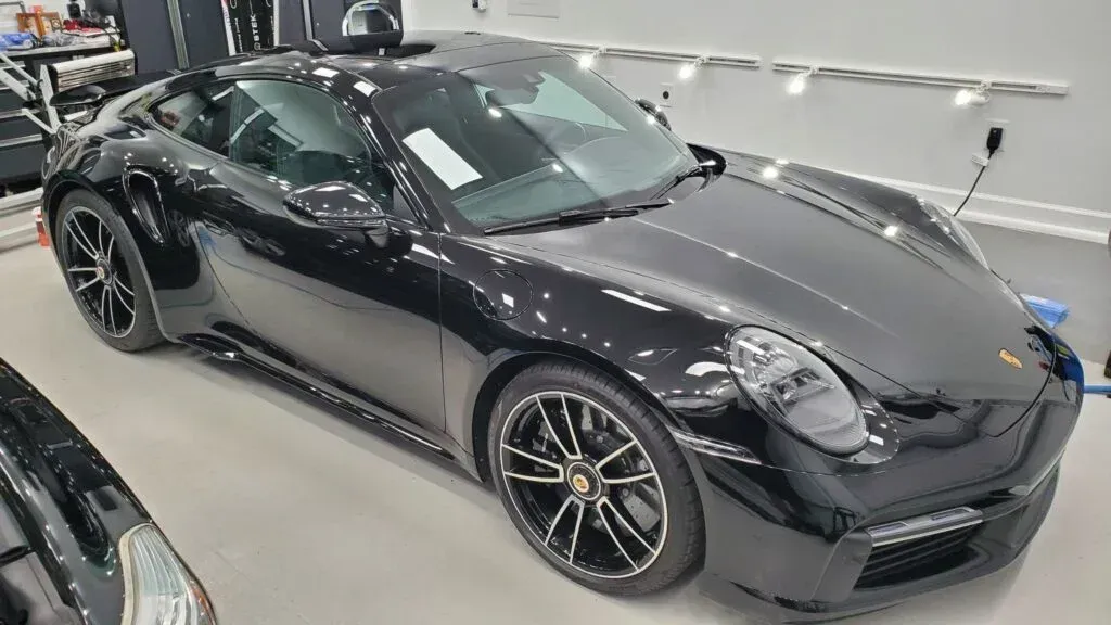 A black porsche 911 is parked in a garage.