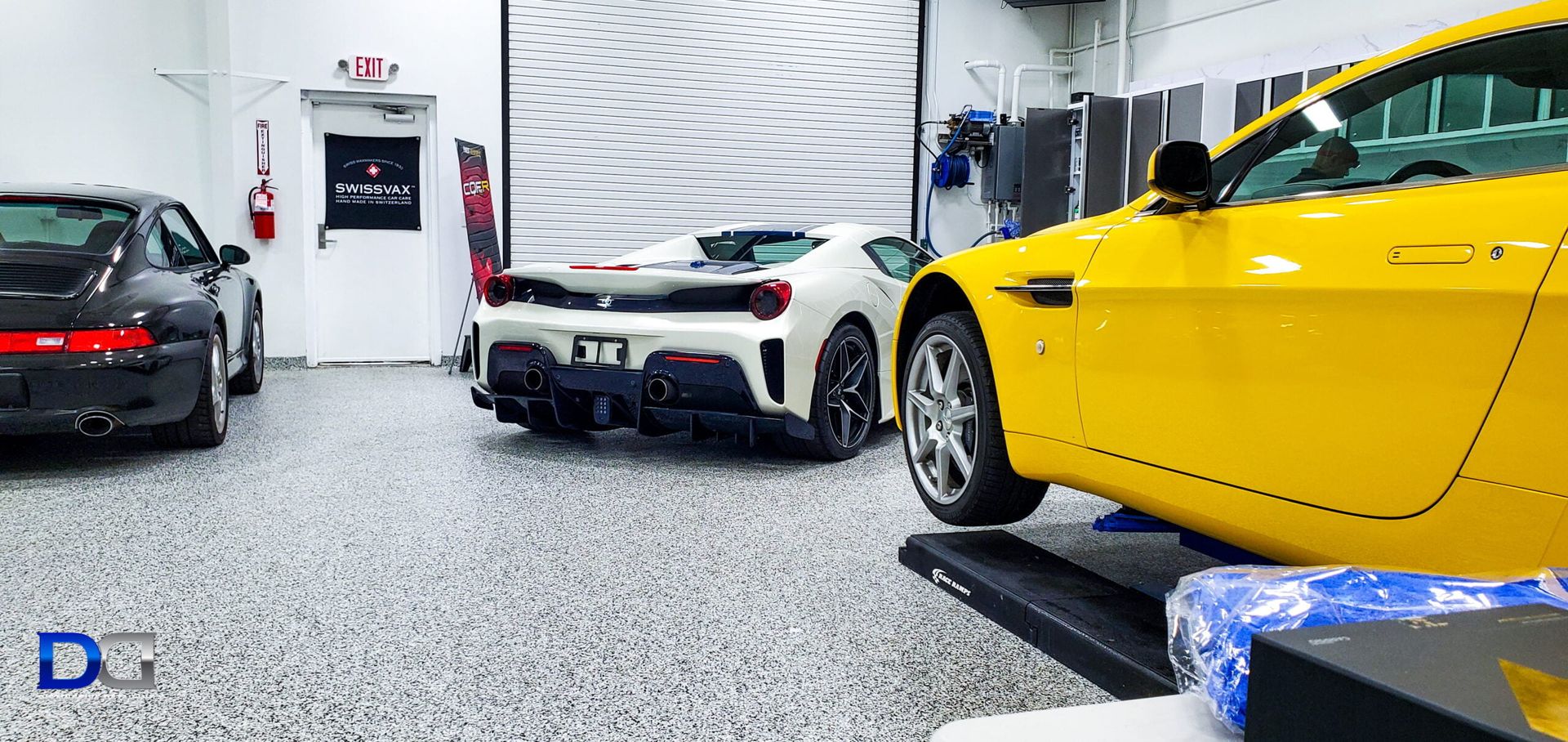 A yellow sports car is being worked on inside a garage with other cars.