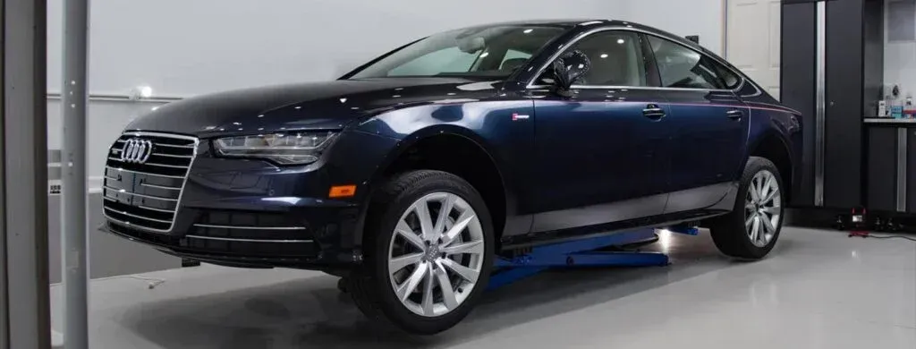 A blue audi a7 is parked on a lift in a garage.