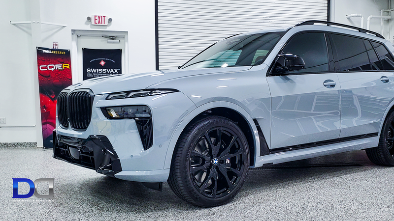 Gray BMW X7 SUV with black rims parked indoors, angled view.
