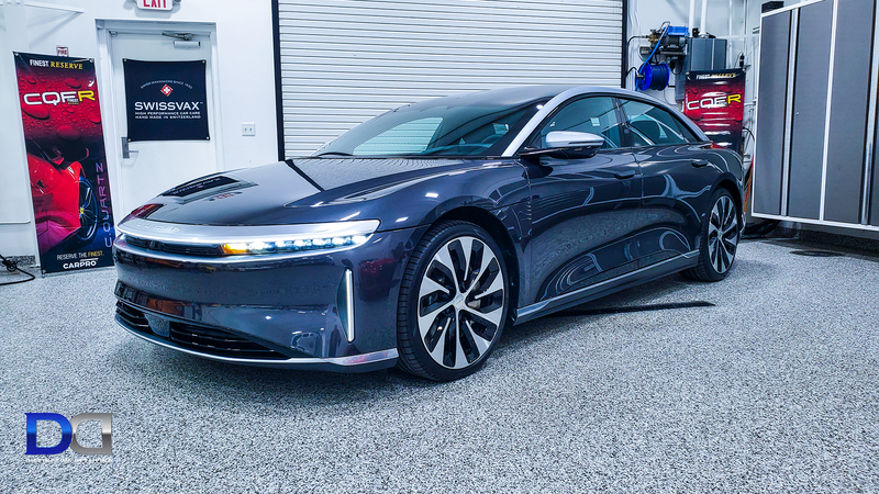 Dark blue Lucid Air electric sedan in a garage setting.