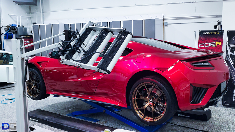 Red Acura NSX on a lift in a workshop; getting alignment.