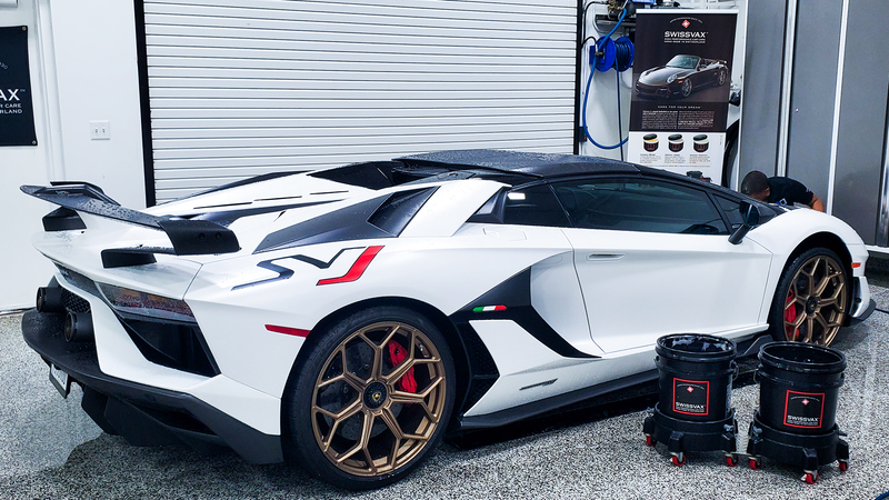 White Lamborghini Aventador SVJ in a detailing shop, gold wheels, black accents.