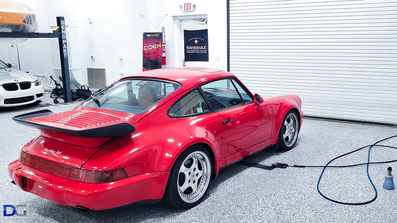 Red Porsche 911 parked inside a garage, connected to a cord.