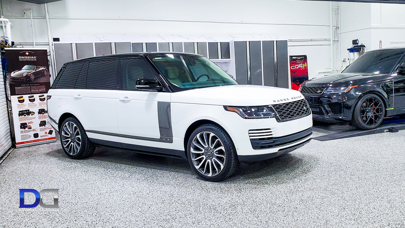 White Range Rover SUV in a garage with a black SUV to the right.